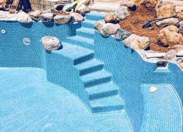 Alternative view of swimming pool with built-in rock feature, created by Pools Builders